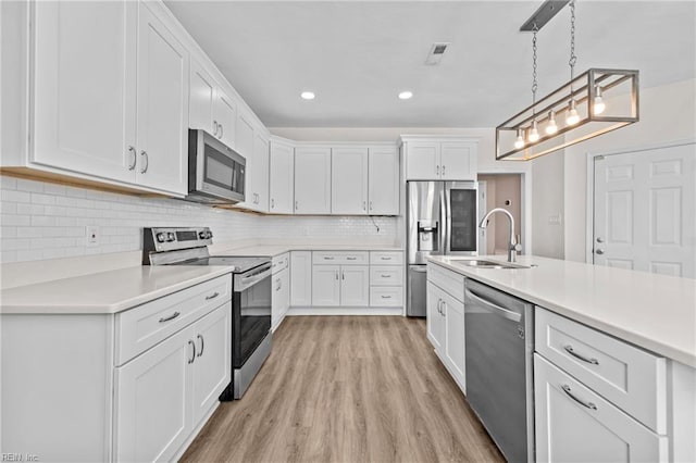 kitchen with stainless steel appliances, sink, pendant lighting, and white cabinets