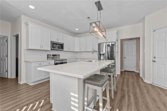 kitchen featuring white cabinetry, appliances with stainless steel finishes, sink, and hanging light fixtures