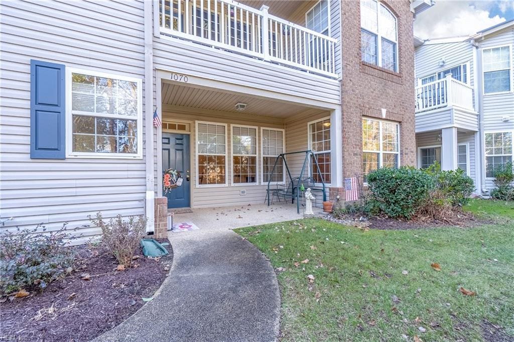 entrance to property featuring a patio area, a lawn, and a balcony