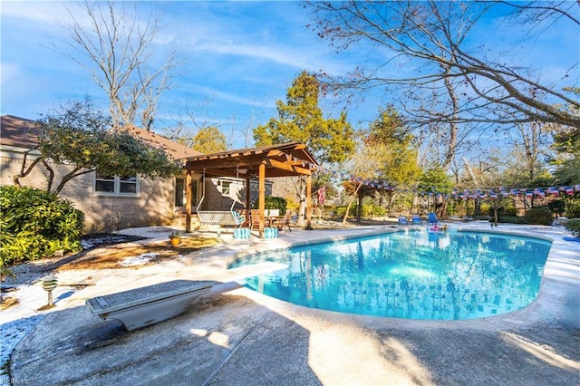 view of swimming pool with a diving board and a patio area