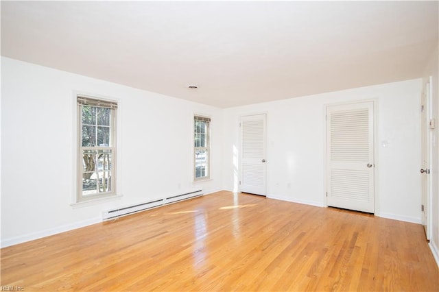 unfurnished room featuring baseboard heating and light wood-type flooring