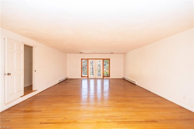 spare room with a baseboard heating unit and light hardwood / wood-style flooring