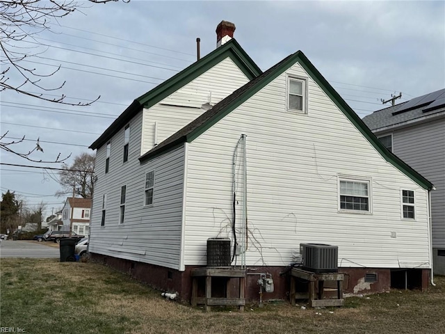 rear view of property featuring a lawn and central AC