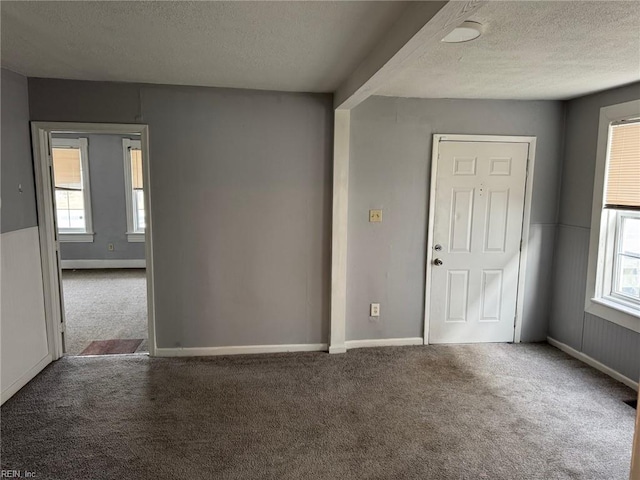 carpeted empty room with a textured ceiling