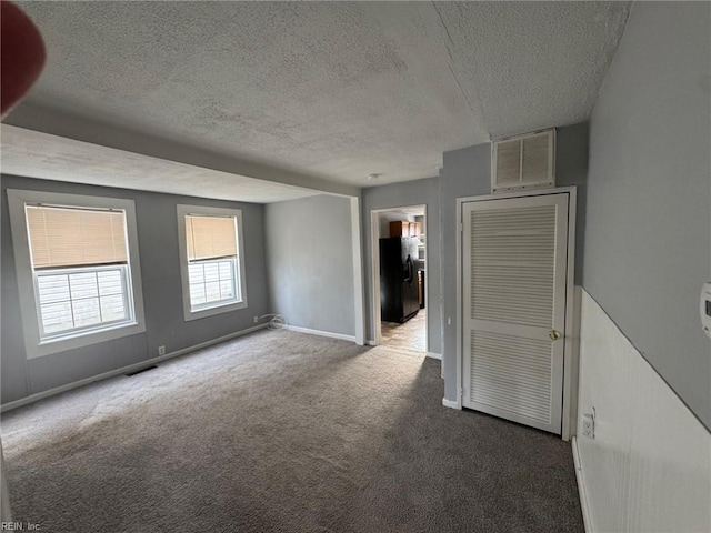 carpeted spare room featuring a textured ceiling