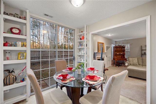 dining room with light carpet, a textured ceiling, and built in shelves