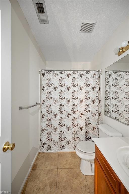 bathroom with a textured ceiling, toilet, tile patterned flooring, and vanity