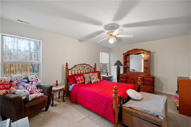 bedroom with ceiling fan, light colored carpet, and a textured ceiling