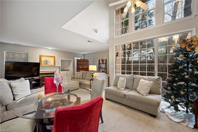 carpeted living room featuring ceiling fan and a towering ceiling