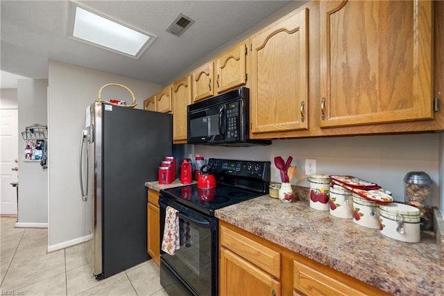 kitchen featuring black appliances, light tile patterned flooring, and light stone counters