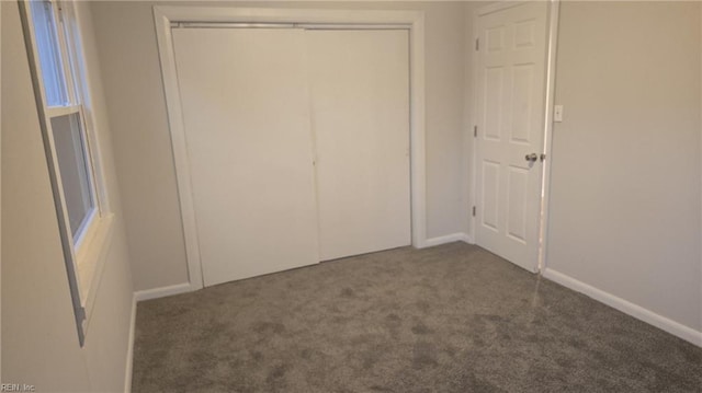 unfurnished bedroom featuring a closet and dark colored carpet