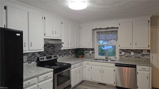 kitchen with sink, white cabinetry, light hardwood / wood-style flooring, light stone countertops, and appliances with stainless steel finishes