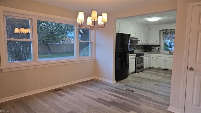 kitchen with hanging light fixtures, black fridge, stainless steel range with electric cooktop, tasteful backsplash, and white cabinets