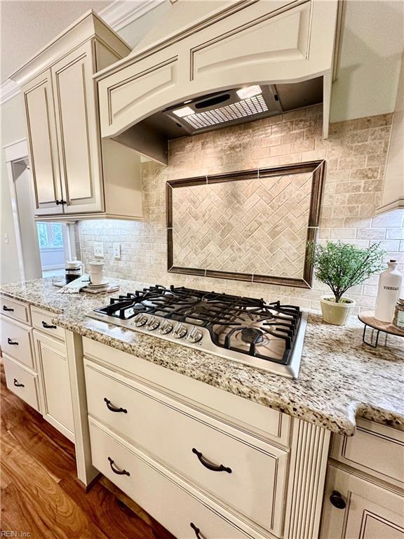 kitchen featuring dark hardwood / wood-style flooring, stainless steel gas stovetop, tasteful backsplash, and cream cabinets