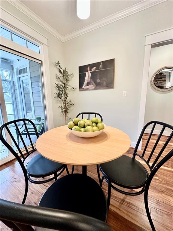 dining space featuring ornamental molding and light hardwood / wood-style flooring