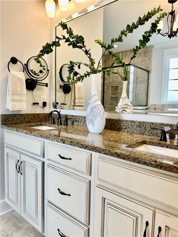 bathroom featuring tile patterned flooring, an inviting chandelier, and vanity