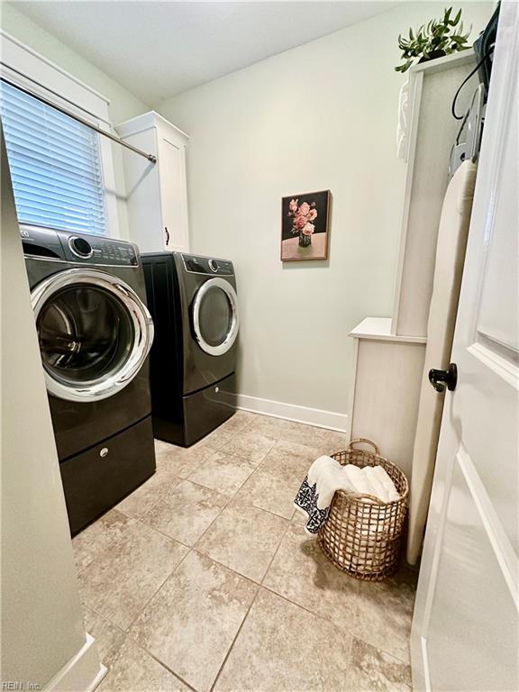 laundry room featuring cabinets, washer and clothes dryer, and light tile patterned flooring