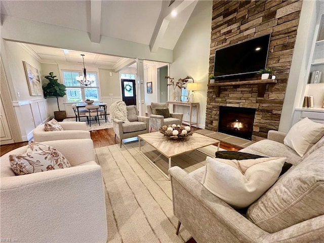 living room featuring light wood-type flooring, an inviting chandelier, lofted ceiling with beams, and a fireplace