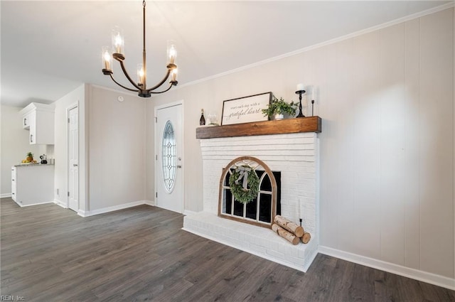 unfurnished living room featuring ornamental molding, dark hardwood / wood-style flooring, a brick fireplace, and an inviting chandelier