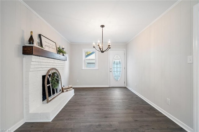 entryway with dark hardwood / wood-style flooring, an inviting chandelier, ornamental molding, and a fireplace