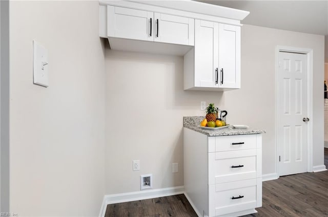 kitchen with white cabinetry, light stone counters, and dark hardwood / wood-style floors