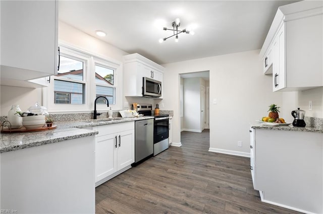 kitchen featuring stainless steel appliances, sink, white cabinetry, light stone counters, and dark wood-type flooring