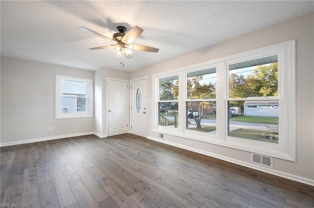 unfurnished room with ceiling fan, dark wood-type flooring, and a textured ceiling