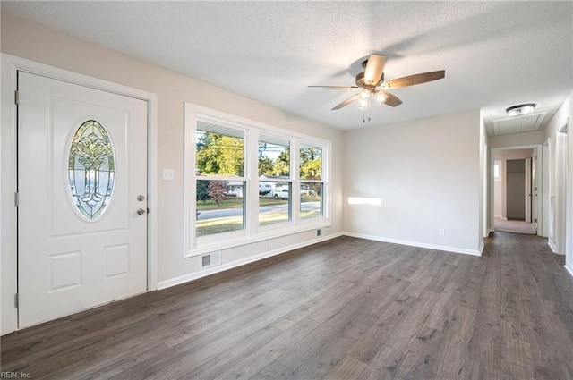 foyer entrance with ceiling fan, dark wood-type flooring, and a textured ceiling