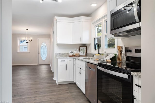 kitchen with stainless steel appliances, sink, white cabinets, an inviting chandelier, and light stone countertops