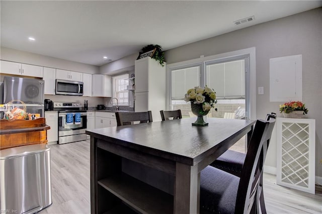 kitchen with sink, white cabinets, light hardwood / wood-style flooring, and stainless steel appliances