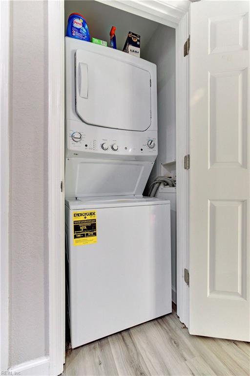 washroom featuring stacked washer and clothes dryer and light wood-type flooring