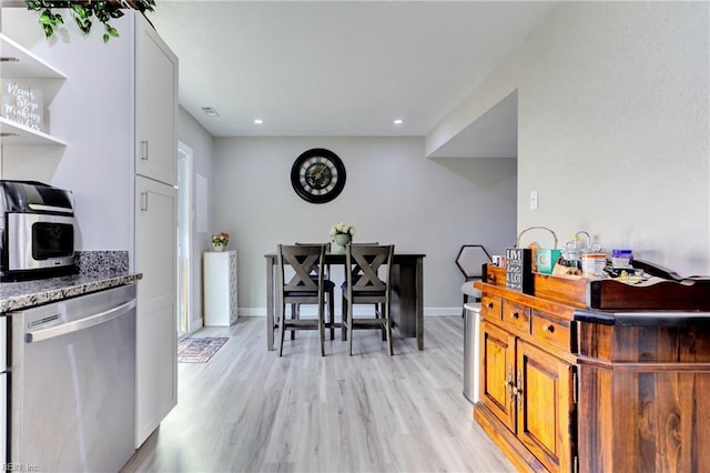 kitchen with light wood-type flooring, dishwasher, and dark stone counters