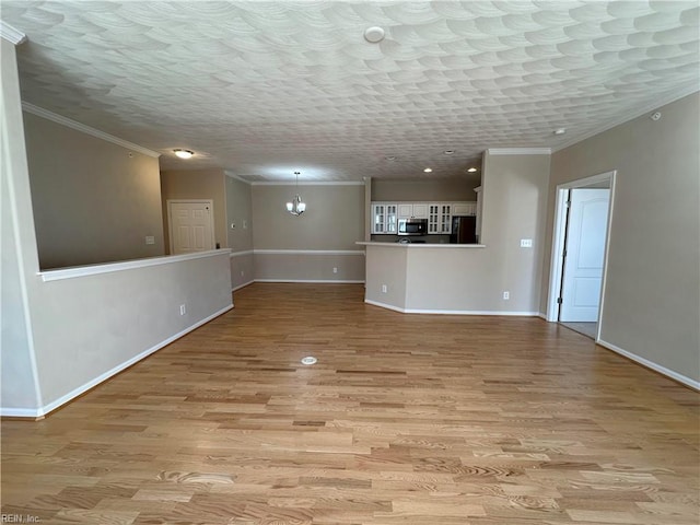 unfurnished living room featuring ornamental molding, an inviting chandelier, and light hardwood / wood-style floors