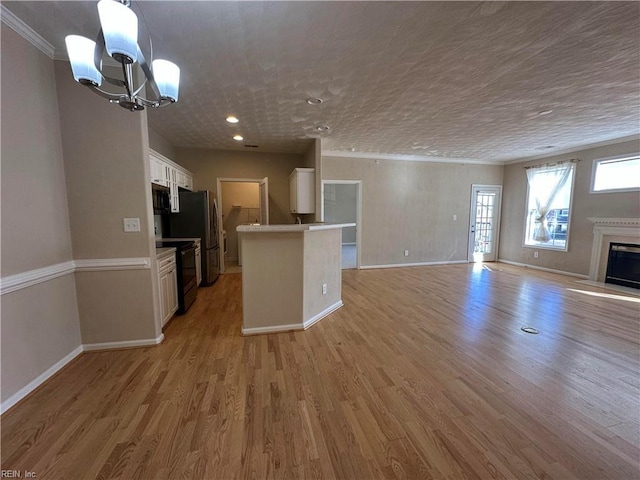 kitchen featuring decorative light fixtures, white cabinetry, black electric range, light hardwood / wood-style floors, and a chandelier