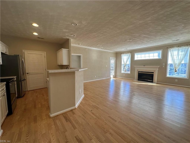 unfurnished living room featuring light wood-type flooring and a textured ceiling