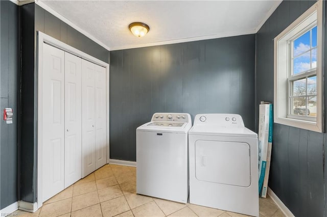 laundry area with light tile patterned floors, washer and dryer, wood walls, and ornamental molding