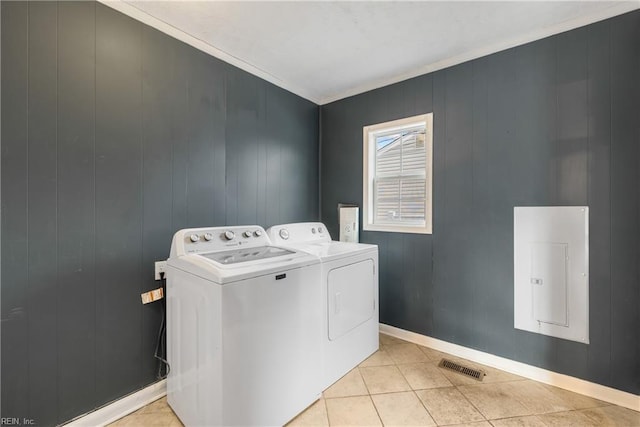 washroom featuring washing machine and dryer, light tile patterned flooring, crown molding, and electric panel