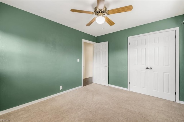 unfurnished bedroom featuring ceiling fan, light colored carpet, and a closet