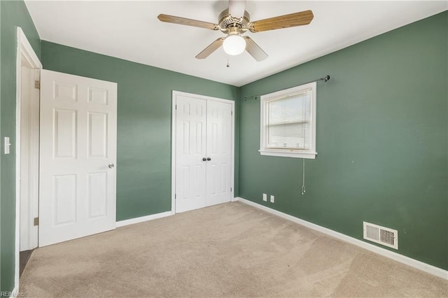 unfurnished bedroom featuring ceiling fan, a closet, and light carpet