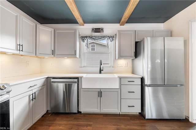 kitchen featuring appliances with stainless steel finishes, dark wood-type flooring, tasteful backsplash, sink, and gray cabinetry