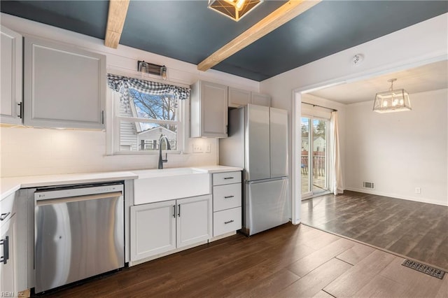 kitchen featuring appliances with stainless steel finishes, dark wood-type flooring, beamed ceiling, sink, and hanging light fixtures