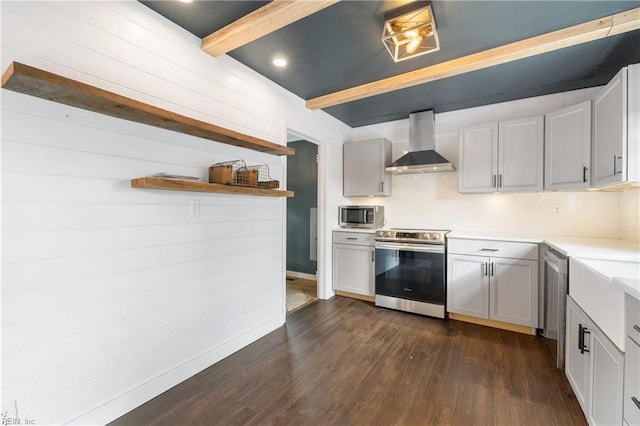 kitchen with beam ceiling, dark hardwood / wood-style floors, wall chimney range hood, and stainless steel appliances