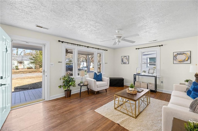 living room featuring a textured ceiling, dark wood-type flooring, and ceiling fan