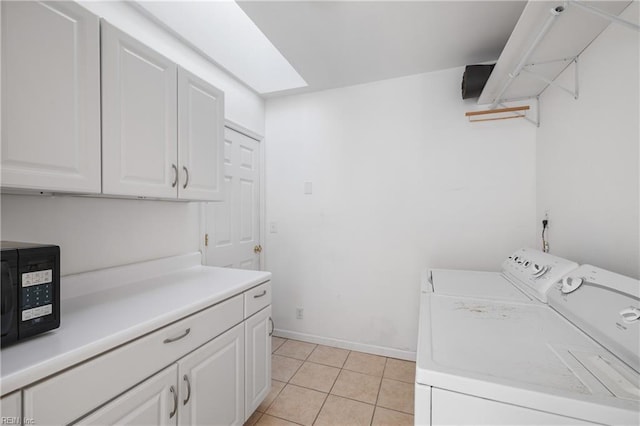 laundry area with cabinets, light tile patterned floors, separate washer and dryer, and a skylight