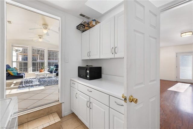 kitchen featuring ceiling fan, light tile patterned floors, and white cabinets