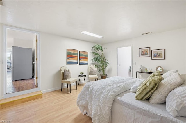 bedroom featuring light wood-type flooring and stainless steel fridge