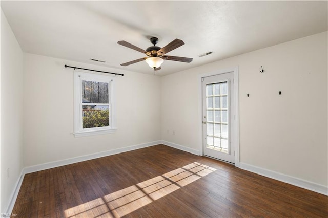 unfurnished room with ceiling fan, dark wood-type flooring, and a wealth of natural light