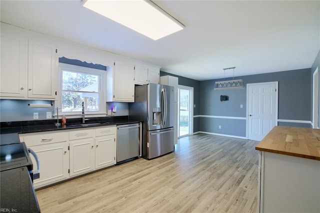 kitchen with white cabinets, appliances with stainless steel finishes, pendant lighting, and sink