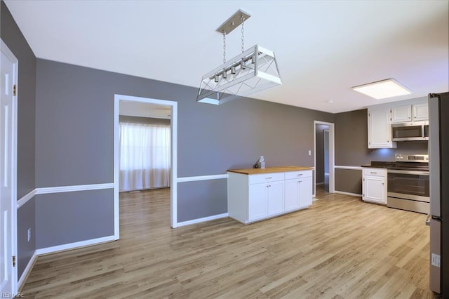 kitchen featuring hanging light fixtures, stainless steel appliances, light hardwood / wood-style floors, wood counters, and white cabinets