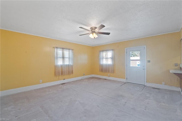 interior space with ceiling fan, a wealth of natural light, crown molding, and a textured ceiling